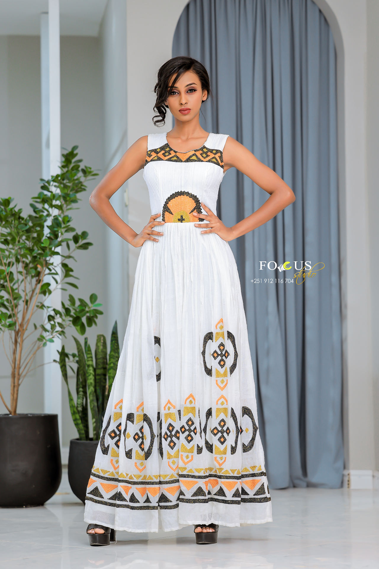 A white flowing dress with geometric black and gold embroidery