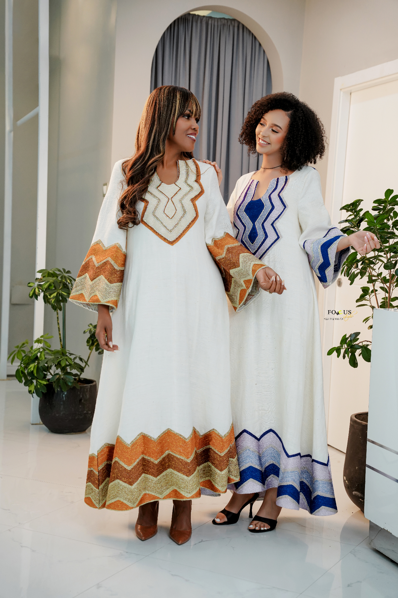 Two models wearing elegant white traditional Ethiopian dresses